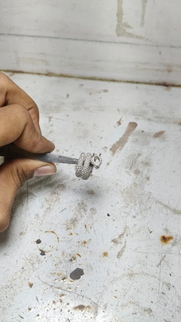 A jeweller finishing the platinum casting of the serpent ring at the bench